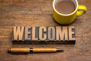 welcome sign - word in vintage letterpress wood type with a cup of coffee against rustic wood, business and hospitality concept